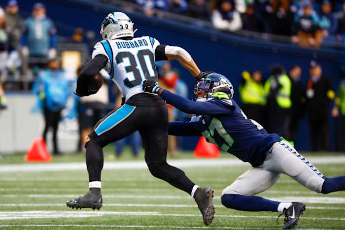 Carolina Panthers running back Chuba Hubbard (30) stiff arms a way from a tackle attempt by Seattle Seahawks cornerback Tariq Woolen (27) during the fourth quarter at Lumen Field.